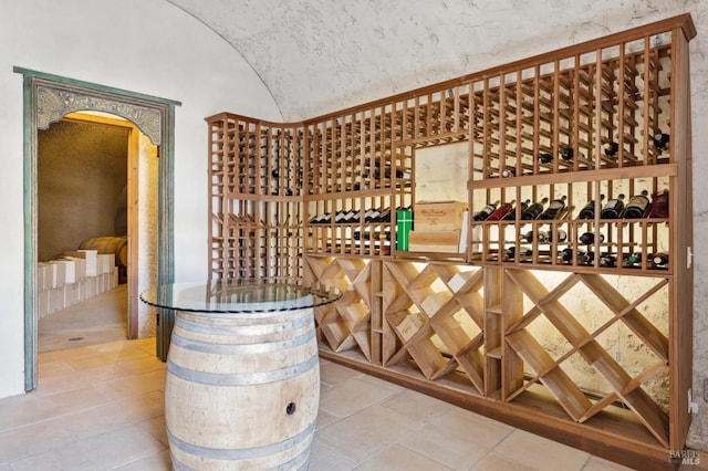 wine room with tile patterned flooring, vaulted ceiling, and arched walkways