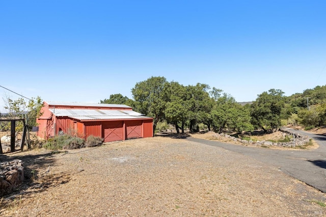 exterior space featuring an outbuilding, a detached garage, gravel driveway, and an outdoor structure