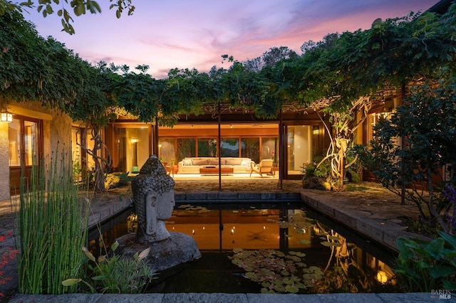 pool at dusk with an outdoor living space and a patio