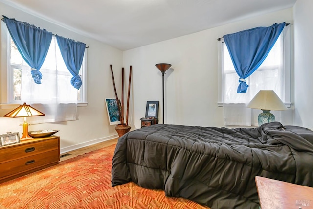 bedroom with light wood finished floors, baseboards, and multiple windows