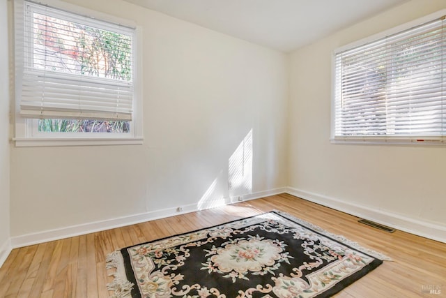 unfurnished room with baseboards, wood finished floors, and visible vents