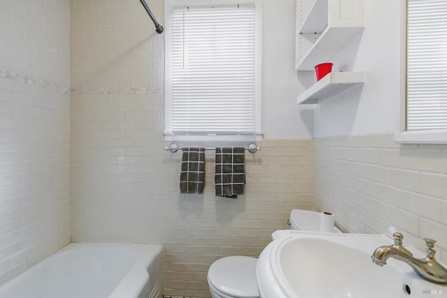 full bathroom with sink, tile walls, toilet, and tiled shower / bath combo