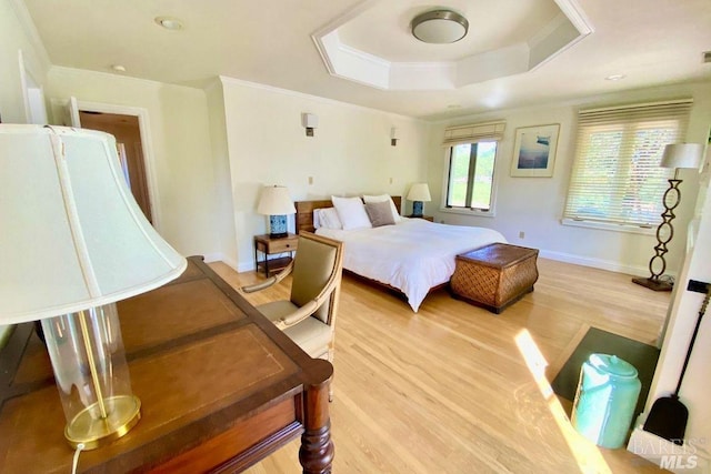 bedroom featuring ornamental molding, light hardwood / wood-style flooring, and a tray ceiling