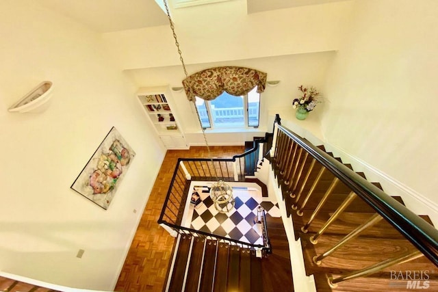 staircase with an inviting chandelier and parquet flooring