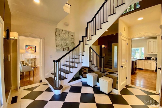 stairs with wood-type flooring and a high ceiling