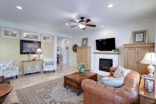 living area featuring baseboards, arched walkways, crown molding, a fireplace, and recessed lighting