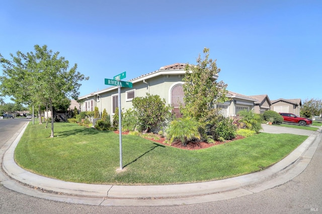 view of side of property featuring a residential view, a lawn, an attached garage, and stucco siding