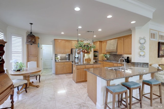 kitchen with dark stone counters, a peninsula, hanging light fixtures, premium range hood, and a sink