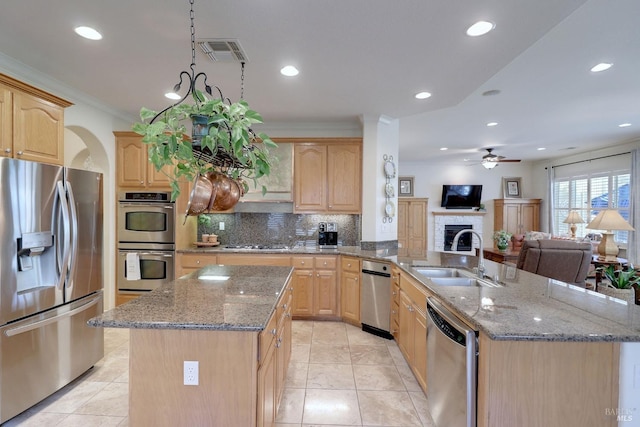 kitchen with appliances with stainless steel finishes, sink, and light brown cabinets