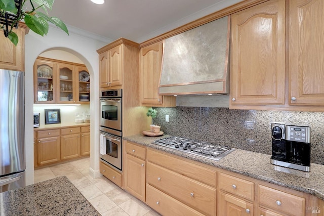 kitchen featuring light brown cabinetry, premium range hood, light stone countertops, and stainless steel appliances