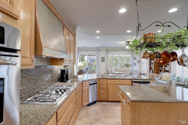 kitchen with custom exhaust hood, kitchen peninsula, light brown cabinetry, and appliances with stainless steel finishes