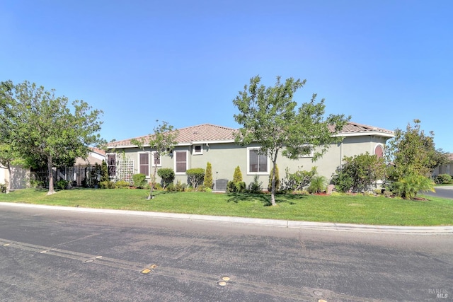 view of front of property featuring fence, a tiled roof, a front lawn, and stucco siding