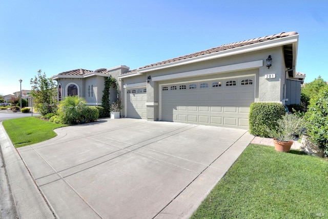 view of front facade featuring a garage, a tile roof, driveway, stucco siding, and a front yard