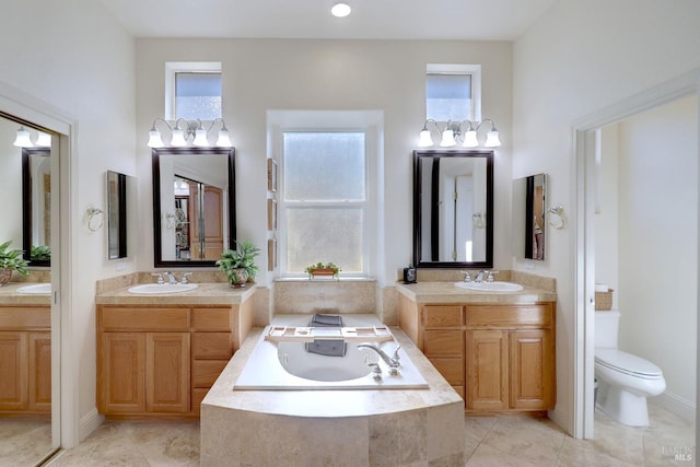 bathroom featuring vanity, tile patterned flooring, toilet, and tiled bath