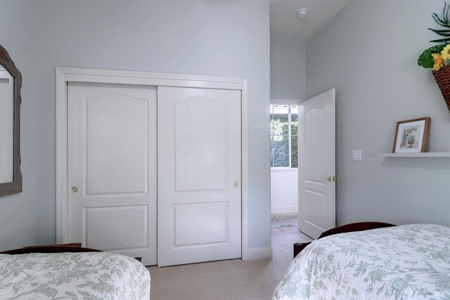 carpeted bedroom featuring a closet and high vaulted ceiling