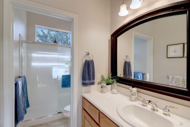 bathroom with a shower with door, vanity, toilet, and tile patterned flooring