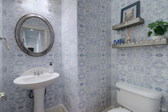 bathroom with toilet and wallpapered walls