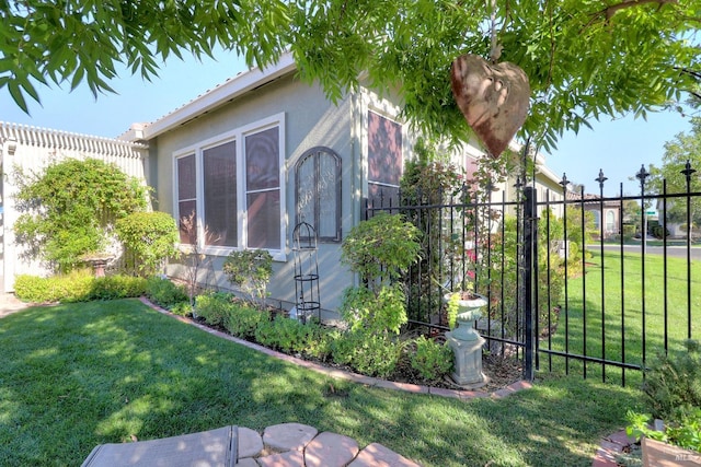 view of side of home featuring stucco siding, a yard, and fence