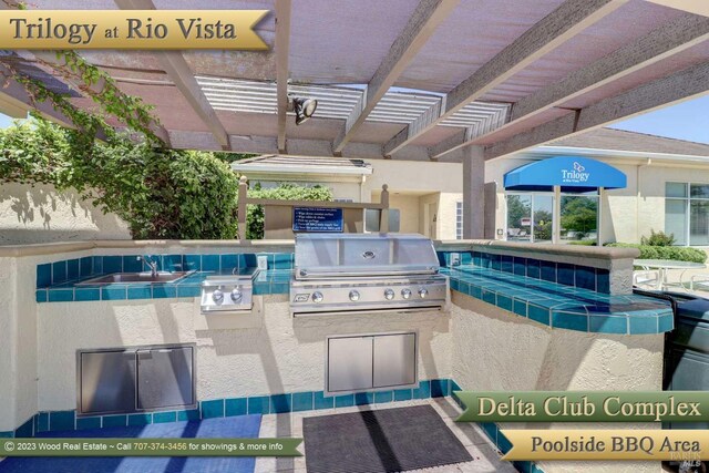 view of pool featuring exterior kitchen, grilling area, and a pergola