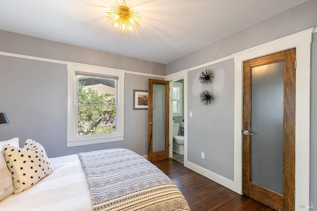 bedroom with ensuite bathroom and dark wood-type flooring