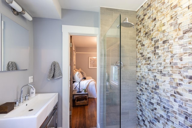 bathroom featuring wood-type flooring, vanity, and tiled shower