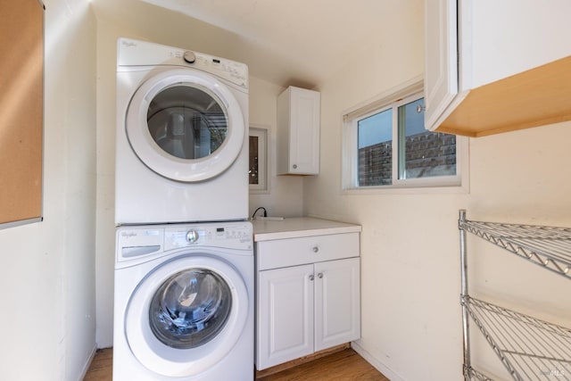 washroom featuring cabinets, light hardwood / wood-style floors, and stacked washer and dryer