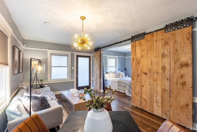 living room featuring plenty of natural light, a barn door, a chandelier, and dark hardwood / wood-style flooring