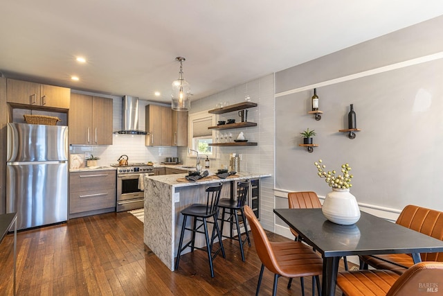 kitchen featuring pendant lighting, sink, wall chimney exhaust hood, stainless steel appliances, and dark hardwood / wood-style floors