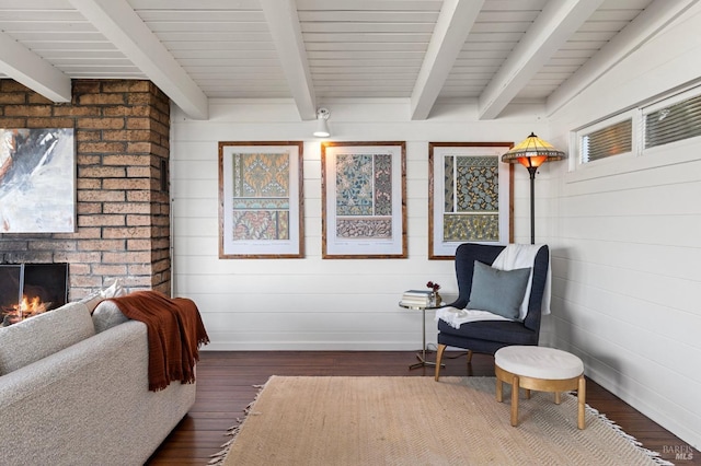 sitting room with beam ceiling, dark hardwood / wood-style flooring, and a fireplace