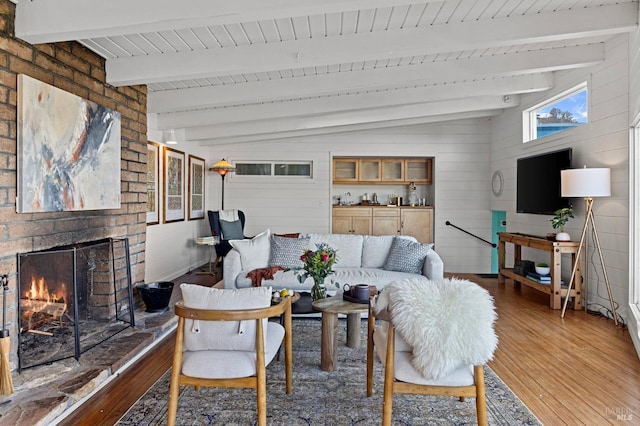 living room featuring vaulted ceiling with beams, hardwood / wood-style flooring, and a fireplace