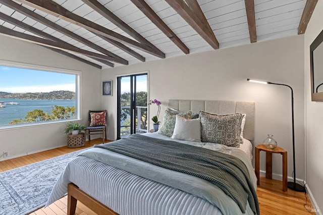 bedroom with a water view, vaulted ceiling with beams, and light wood-type flooring