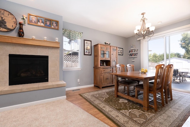 dining room featuring a notable chandelier, a fireplace, plenty of natural light, and light hardwood / wood-style floors