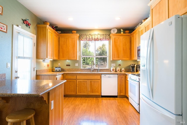 kitchen featuring sink, light hardwood / wood-style floors, white appliances, and a wealth of natural light