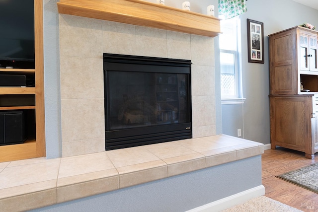 interior details with a tile fireplace and hardwood / wood-style floors