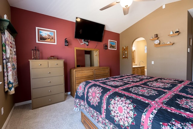 bedroom featuring light carpet, vaulted ceiling, ensuite bathroom, and ceiling fan