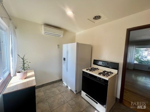 kitchen with a wall unit AC, light wood-type flooring, and white appliances