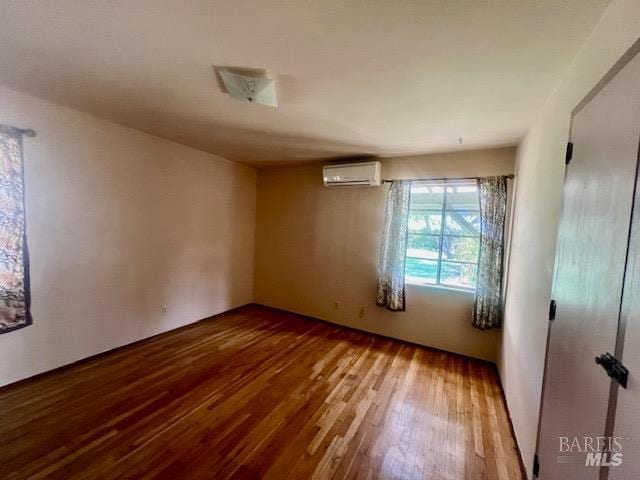 unfurnished room featuring hardwood / wood-style flooring and a wall mounted AC