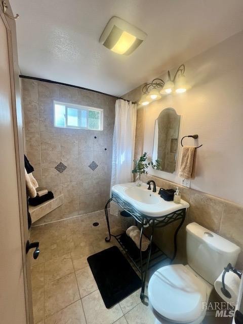 bathroom featuring sink, curtained shower, toilet, tile walls, and tile patterned flooring