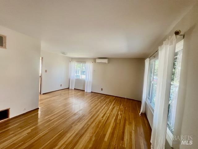 empty room featuring light hardwood / wood-style floors and a wall mounted air conditioner