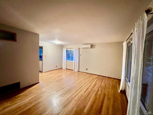 empty room with light hardwood / wood-style floors and a wall unit AC