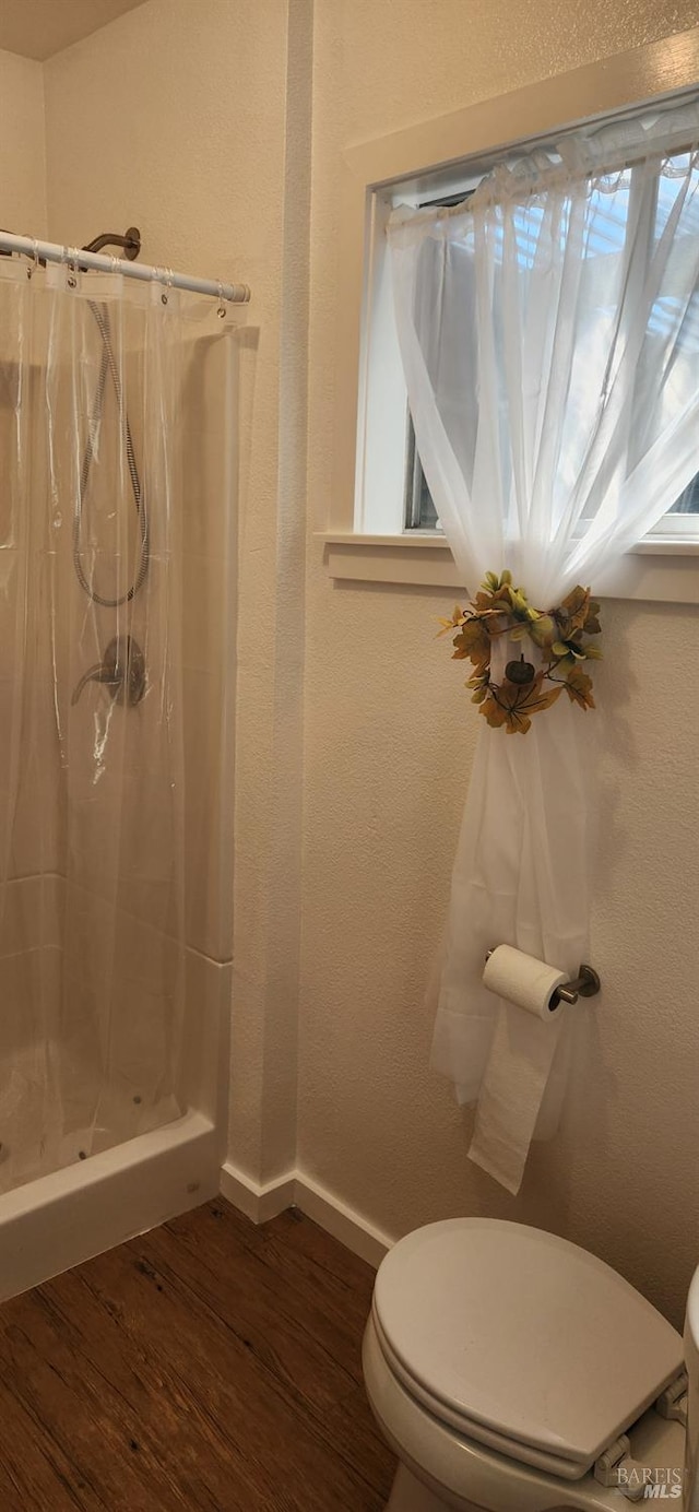 bathroom featuring wood-type flooring, toilet, and a shower with shower curtain