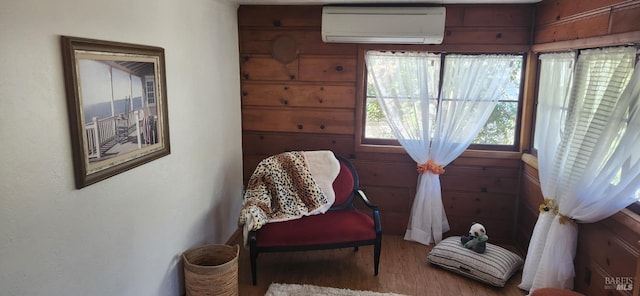 sitting room featuring hardwood / wood-style flooring, wooden walls, and a wall mounted AC