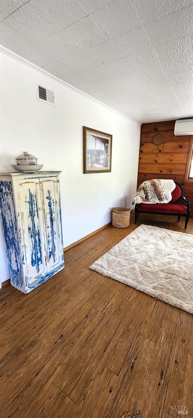 living area with an AC wall unit and hardwood / wood-style flooring