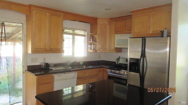 kitchen featuring stainless steel appliances, dark countertops, a sink, and open shelves