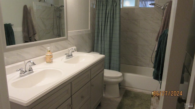 bathroom featuring toilet, double vanity, a sink, and shower / bath combo with shower curtain