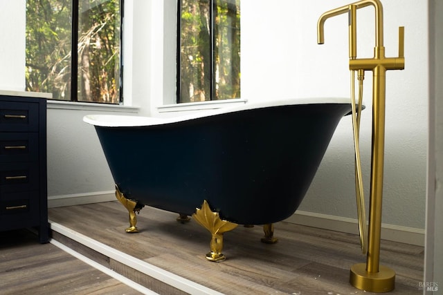 room details with a freestanding bath, wood finished floors, and baseboards