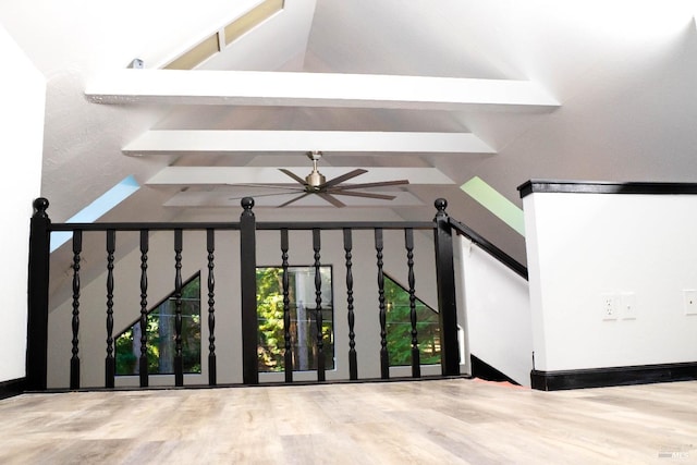 interior space with wood finished floors, a ceiling fan, beam ceiling, and a gate