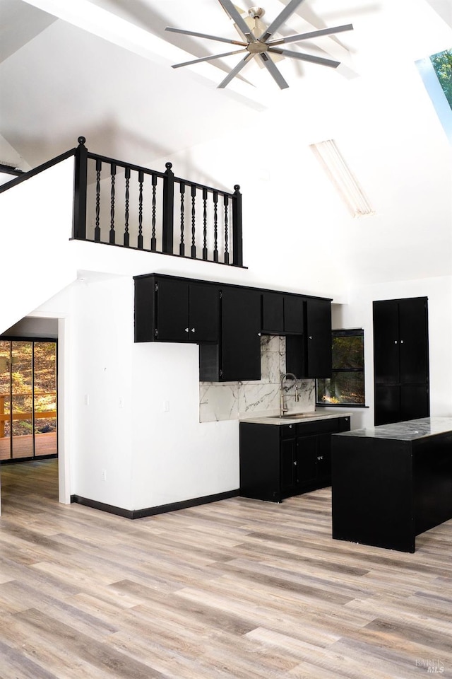 kitchen with a sink, light wood finished floors, and dark cabinets