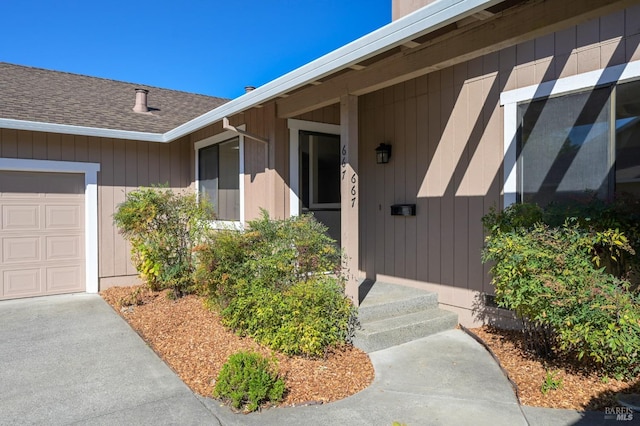 doorway to property with a shingled roof and an attached garage