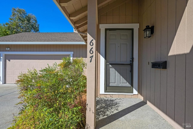 doorway to property featuring a shingled roof and an attached garage